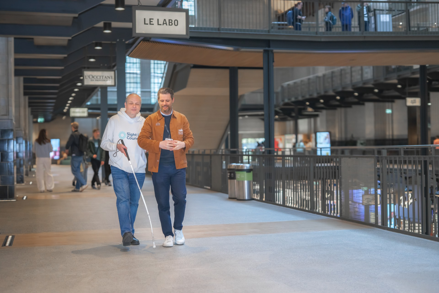A man with a long cane is given sighted guide