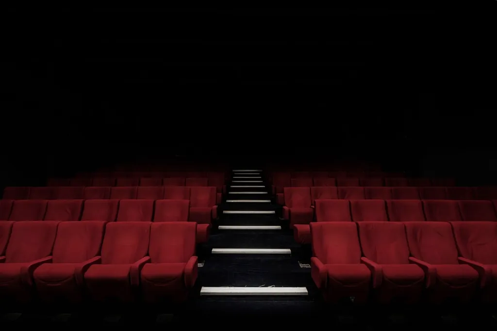 Auditorium with rows of red seats and lit steps running down the centre aisle