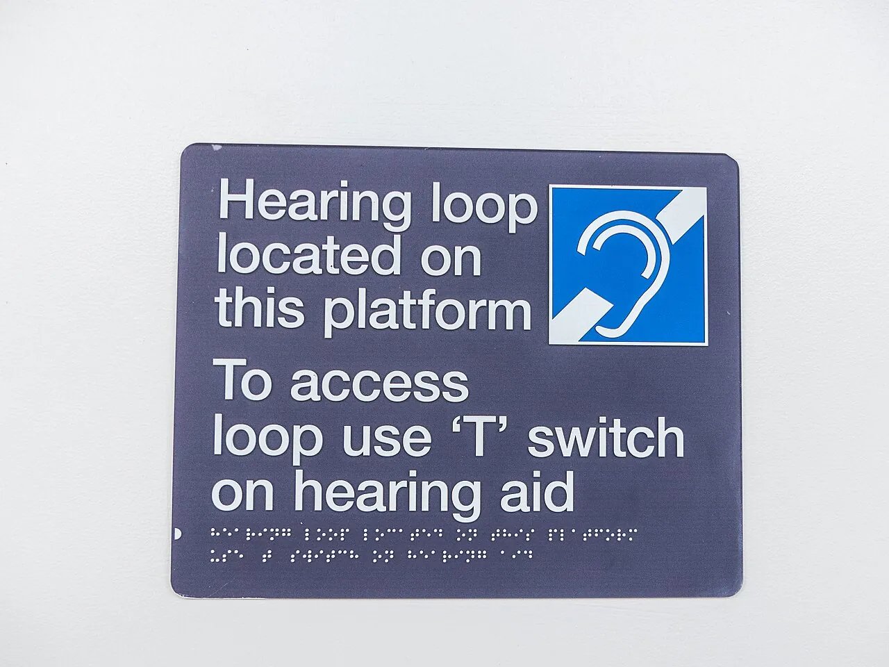 Blue sign with the hearing loop symbol explaining how to use the T switch on a hearing aid